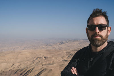 Portrait of man with sunglasses standing against landscape