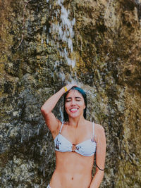 Portrait of smiling young woman standing on rock
