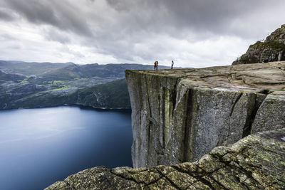 Man standing on rock by sea against sky