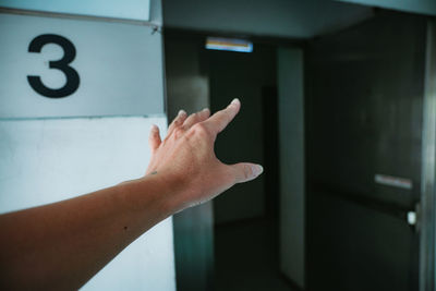 Midsection of person hand with text on wall