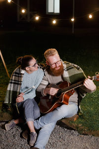 Men sitting on guitar at night