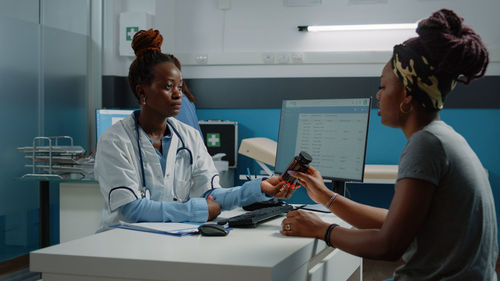 Doctor giving medicine while talking with patient at home