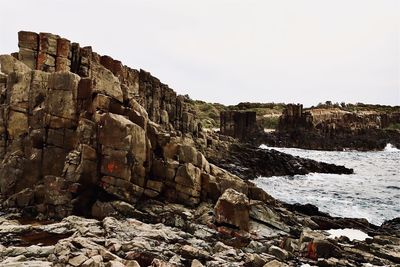 Rock formations by sea against clear sky