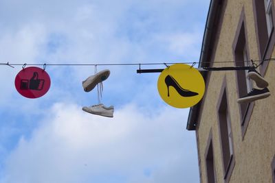Low angle view of road sign hanging against sky
