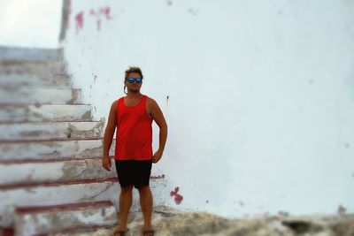 Portrait of young woman standing against wall