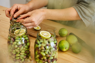 Woman prepares fermented olives in glass jars in the kitchen. autumn vegetables canning.