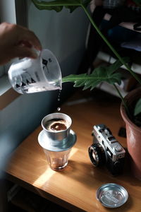 Close-up of hand pouring coffee in cup on table