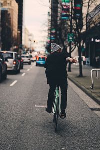 Person showing obscene gesture while riding bicycle on road