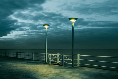 Cloudy sky, the sea and 2 lanterns at dusk on a promenade on the baltic sea