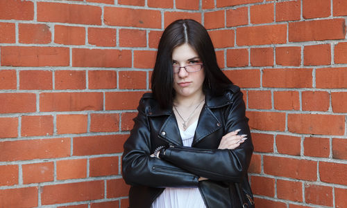 Young beautiful brunette girl in black jacket  stands near wall of gothic church  outdoor closeup