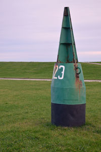 Buoy on grassy field against sky