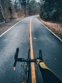 Personal perspective of man riding bicycle on road