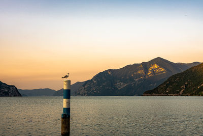 Lighthouse by sea against sky during sunset