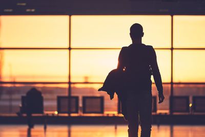 Silhouette man walking at airport during sunset