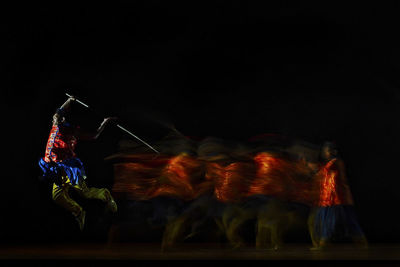 Low angle view of man dancing against black background at night