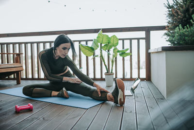 Woman sitting on potted plant at home