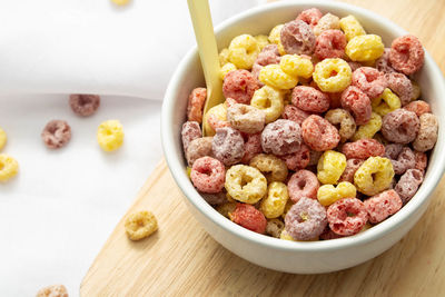 Healthy food concept, colorful ring cereals in bowl on saucer wooden and falling on white cloth.