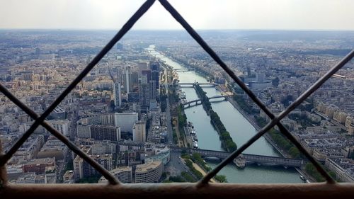 Aerial view of buildings in city seen through chainlink fence