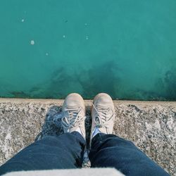 Low section of man standing on retaining wall by sea