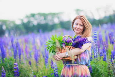 Young attractive woman holding a basket full of lupine flowers