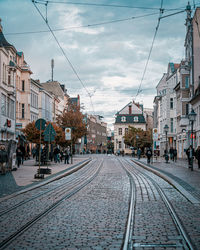 Railroad tracks amidst buildings in city against sky