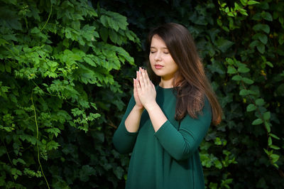 Beautiful young woman standing against plants