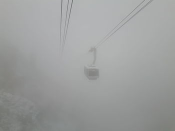 Overhead cable car against sky during foggy weather