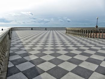 Tiled floor by sea against sky