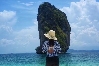 Rear view of woman standing by sea against sky