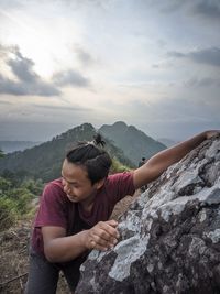 Man on rock against mountains against sky