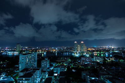 Illuminated cityscape against cloudy sky