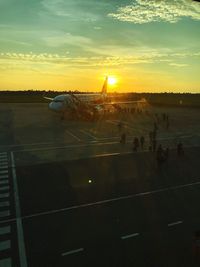 Airplane on runway against sky during sunset