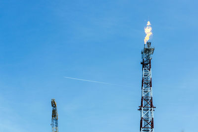 Low angle view of communications tower against blue sky