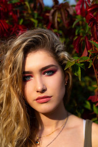 Portrait of beautiful young woman with make-up against plants