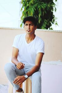 Full length of young man sitting outdoors