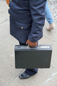 Low section of businessman with suitcase standing on footpath