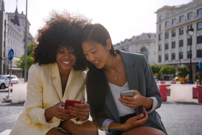 Multiracial friends sharing smart phones in city