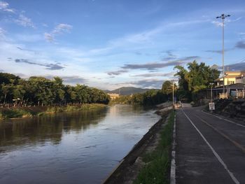 Road by trees against sky