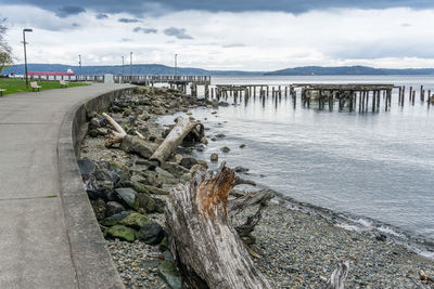 Driftwood on bridge over sea against sky