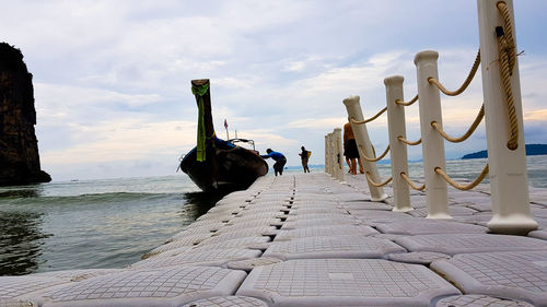 Panoramic view of people on footpath by sea against sky