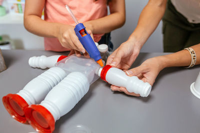 Student and teacher making recycled toy robot with hot melt glue gun