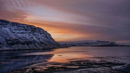 Scenic view of lake by mountains against sky during sunset