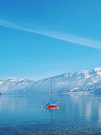 Sailing boat on tranquil clear blue lake in luxury destination in swiss alps, snowcapped mountains