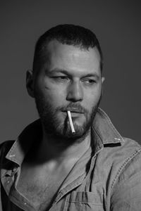 Close-up of man smoking cigarette against gray background