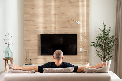 Rear view of woman sitting on sofa at home