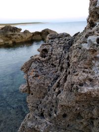 Rock formation on beach against sky