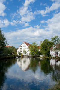 Houses by lake and buildings against sky