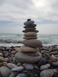 Stack of stones on beach against sky