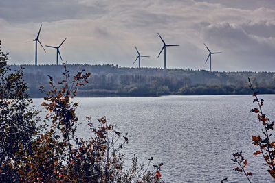 Wind turbines in water against sky