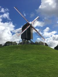 Low angle view of traditional windmill on hill against sky